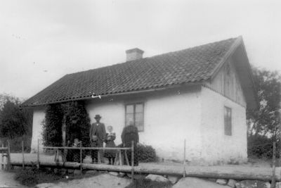 1 man 2 kvinnor och 3 barn framför byggnad
