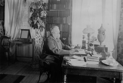 Man sittande vid skrivbord
Nyckelord: Lampa Bokhylla Spegel Tapet Karaff Skrivbord