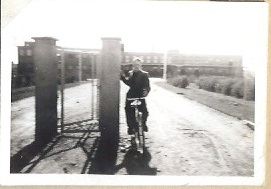 Man på cykel vid fabriksport
