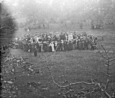 Stor grupp festklädda människor på äng
