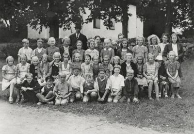 Elever och lärare framför byggnad
