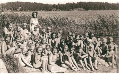 Barn i simskola med ledare invid sjö
