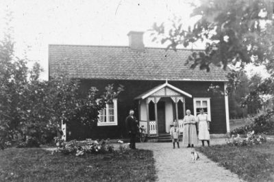 Man två kvinnor och en flicka framför byggnad
