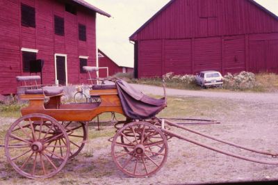 Gammal vagn vid ladugård
