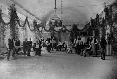 Festklädda män i samlingslokal
