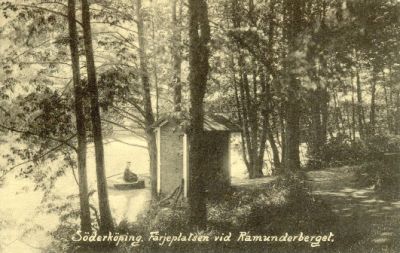 Roddbåt vid båtplats med kioskbyggnad på stranden
