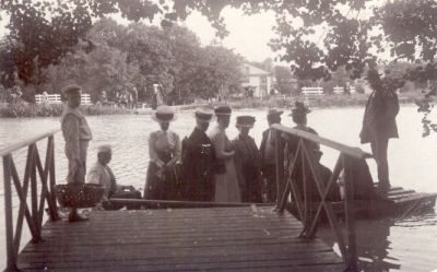 En grupp människor stående i roddbåt invid brygga
