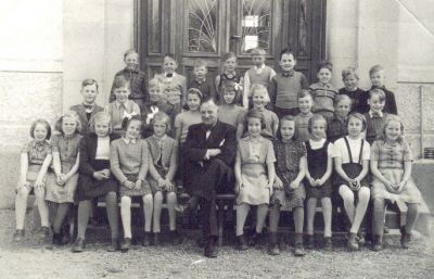 Skolelever och lärare framför byggnad
