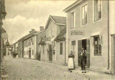 Gatuparti med 3 personer framför cigarraffär
