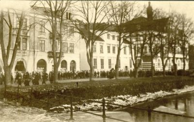Folktåg på gata utmed vattendrag
