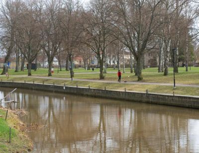 Kvinna med hund i park invid vattendrag
