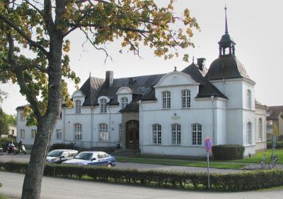 Stor vitputsad byggnad med torn och tinnar.
