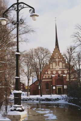 Röd kyrka vid vattendrag
