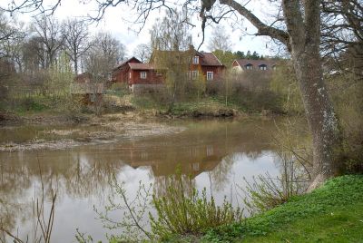 Rött hus på höjd invid vattendrag
