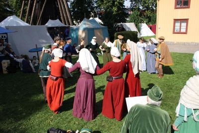 Medeltidsklädda i dans på gräsmatta
