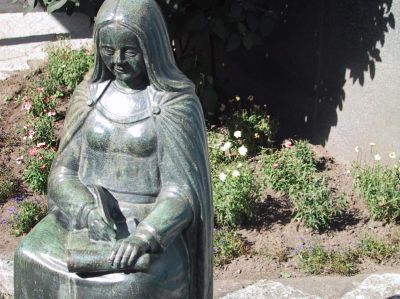 Staty av kvinna som sitter och skriver

