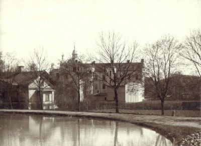 Större putsad bostadsfastighet invid vattendrag
